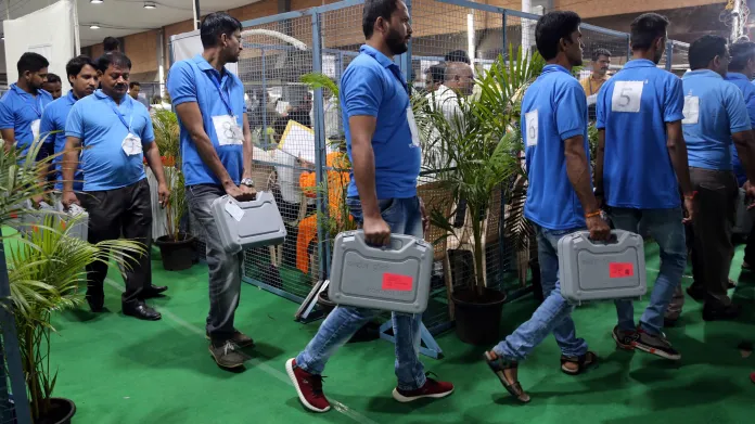 Členové volební komise v Bombaji nesou stroje na sčítání hlasů