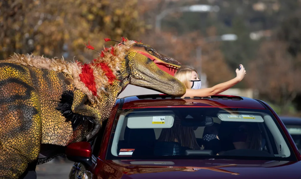 Americká herečka Samantha Bailey si dělá selfie s „dravcem“ v Jurském parku v americké Pasadeně. Park je otevřený pro zájemce, kteří mohou expozici pozorovat pouze z auta. Pro pěší je park z koronavirových důvodů uzavřen