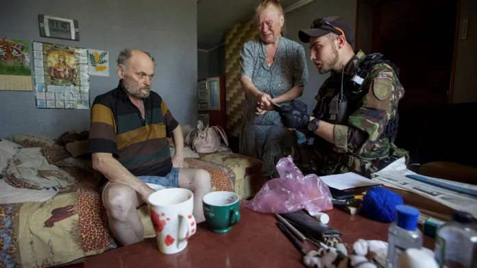 Ukrajinské úřady evakuují lidi z válkou zmítaného východu Ukrajiny. Policista kontroluje totožnost civilistů před evakuací obce Novomichajlivka