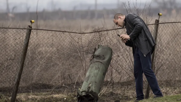Muž fotografuje zbytek munice v blízkosti místa požáru