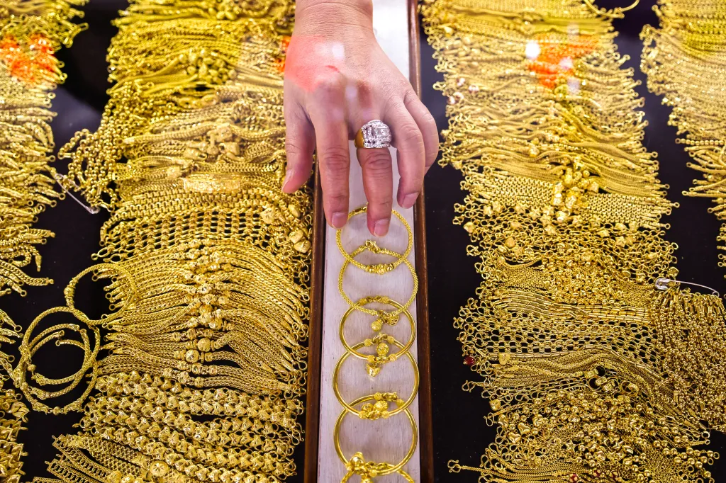 Prodavač aranžuje zlaté náramky v klenotnictví v čínské čtvrti v Bangkoku