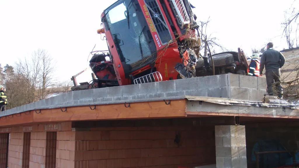 Prázdný tahač na dřevo havaroval na střechu přístavby