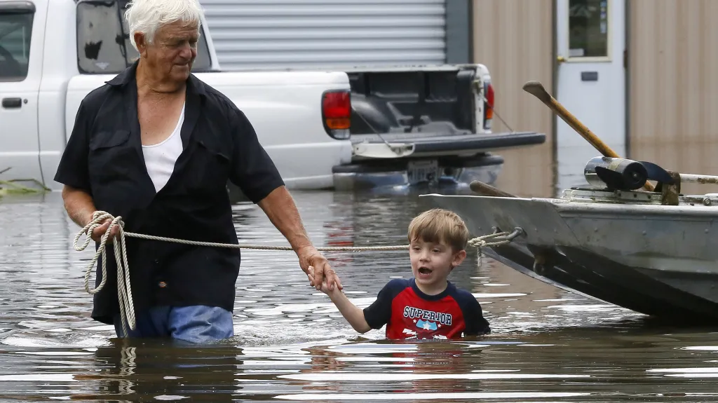 Dědeček se svým čtyřletým pravnukem se brodí vodou poté, co se jim zaplavil dům