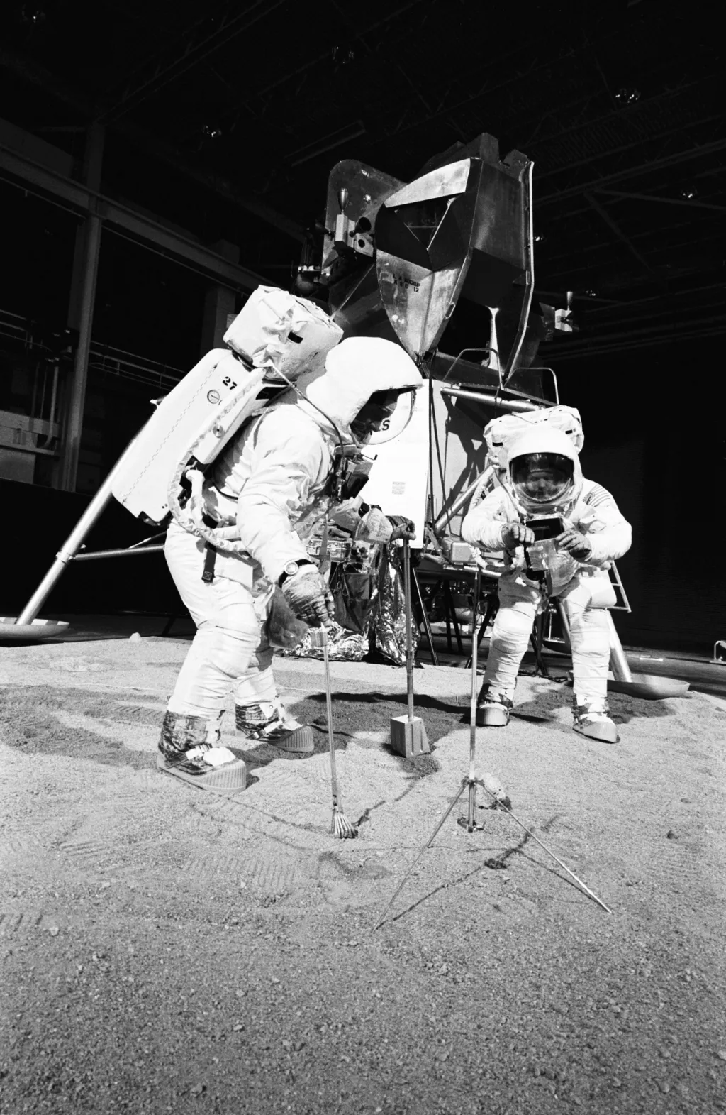 Dva členové mise se účastní tréninku používání měsíčních nástrojů na povrchu Měsíce. Zkouška proběhla v uzavřené budově dne 22. dubna 1969. Ke sběru vzorků jsou použity lopatka, kleště a pytel k převozu.