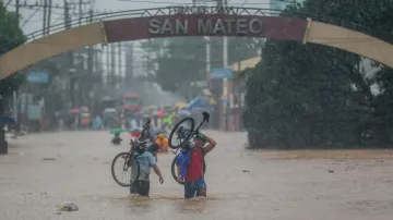 Dva cyklisté se brodí zaplavenou ulicí