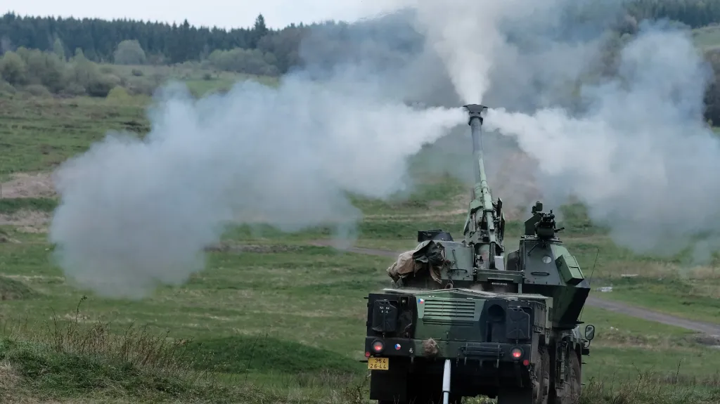 Výstřel. Cíl je 15 kilometrů daleko. Všimněte si rozsvícených brzdovek. Vozidlo při výstřelu „stojí na brzdách“, aby se co nejvíc utlumil zpětný ráz děla