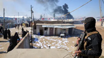 Příslušník syrské armády stojí na stráži v detenčním táboře al-Húl s příbuznými členů takzvaného Islámského státu