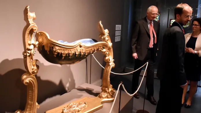 Lichtenštejnský kníže Hans Adam II. na zahájení výstavy, u zlacené dětské kolíbky