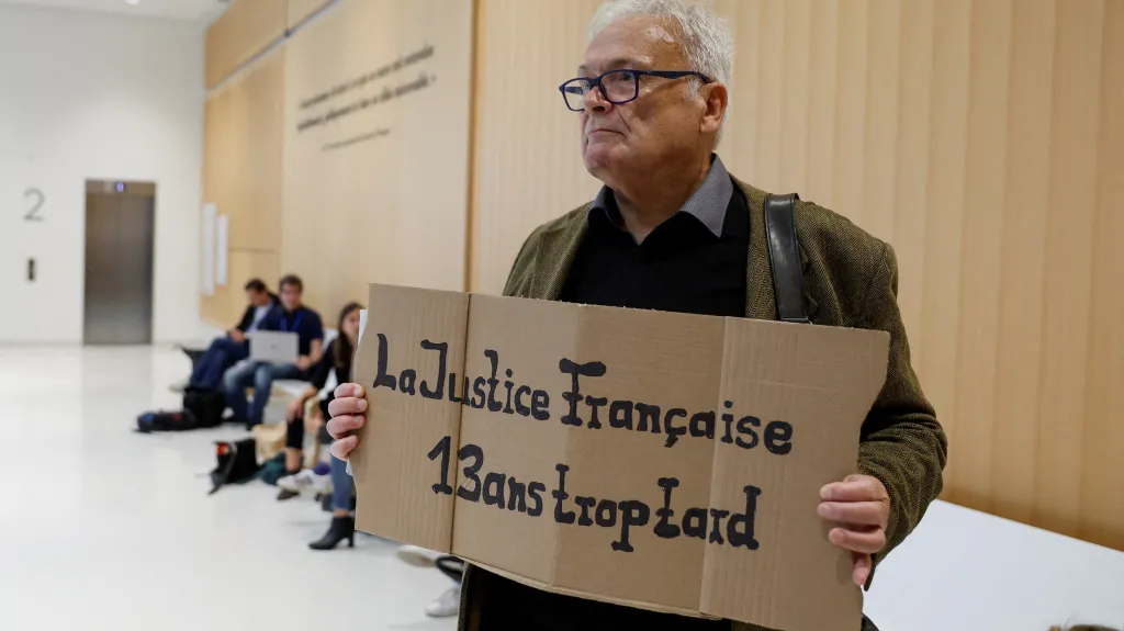 Wilfried Schmid, rodinný příslušník oběti, drží transparent s nápisem „Francouzská justice má 13 let zpoždění“