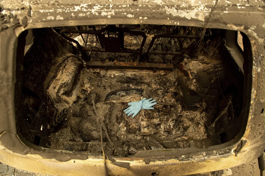 Záchranářské rukavice v ohořelém vraku auta v požárem zničeném kalifornském městě Paradise