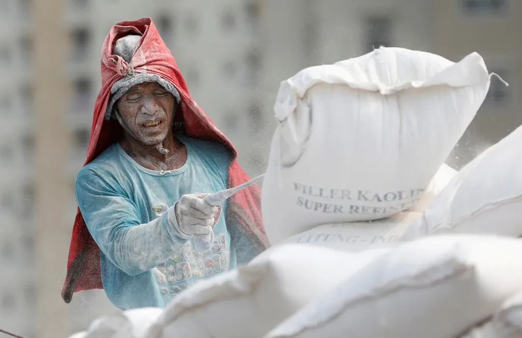 Dělník skládá náklad kaolinu z lodi v přístavu Sunda Kelapa v Indonésii