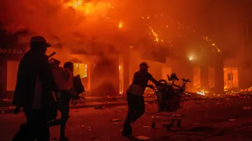 Pracovníci zachraňují své věci z hořících obchodů během protestů