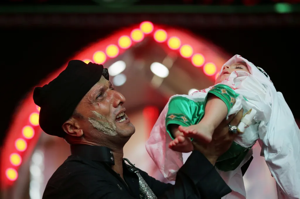 Poblíž Karbaly muž zvedá své vnouče jako symbolické připomenutí ztráty Husajna