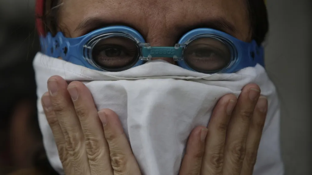 Venezuelský demonstrant se brání před slzným plynem