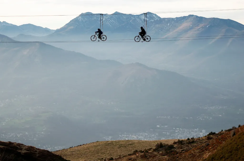 Turisté na speciálních kolech, která jsou zavěšená na lanech, se přemisťují nad pyrenejskou krajinou ve francouzském Beaucens
