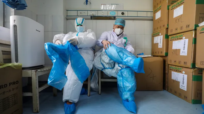 Zdravotníci v nemocnici v čínském Wu-chanu si oblékají ochranné obleky