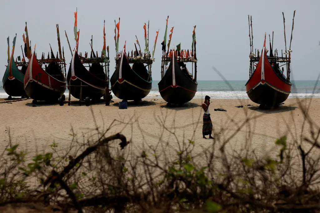 Převaděč lidí telefonuje na pláži u uprchlického tábora Rohingů po ztroskotání lodi v Andamanském moři