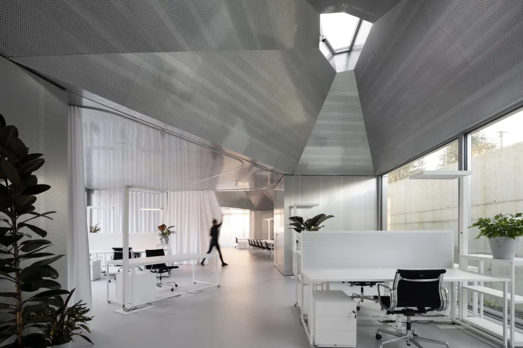 Moduly s lichoběžníkovým půdorysem ukrývají kompletní zázemí, od technické místnosti přes šatny, kuchyňku, sanitární zařízení až po multimediální vybavení nebo showroom. Open space mezi moduly lze pomocí systému závěsů proměnit podle potřeb