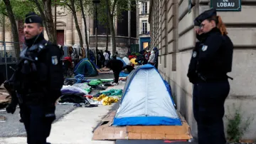 Francouzští četníci stojí na pozicích, zatímco migranti sbírají své věci na náměstí Saint-Gervais poblíž pařížské radnice.