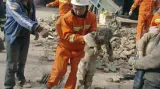 Záchranář vynáší dítě z trosek domu zničeného zemětřesením