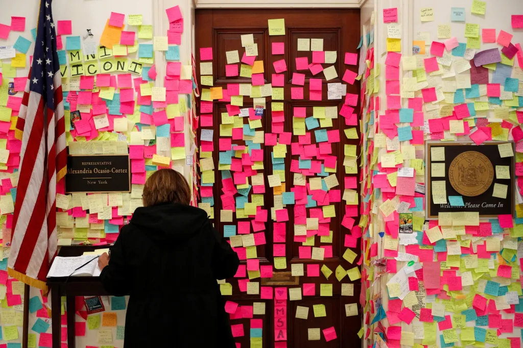 Žena se podepisuje v knize návštěv uprostřed stovek poznámkových papírků, kde příznivci zanechali vzkazy pro kongresmanku Alexandrii Ocasio-Cortezovou před hlasováním o impeachmentu prezidenta Donalda Trumpa