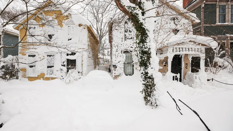 Stěrače zasypaného auta jsou vidět před zasněženými domy po bouři v Buffalu