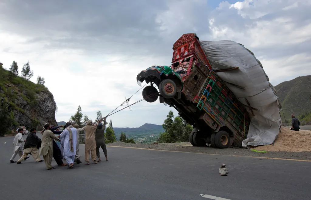 Muži se snaží pomocí lan postavit zpátky na kola dodávkový vůz na silnici v Dargai, v okrese Malakand, asi 165 kilometrů severozápadně od hlavního města Pákistánu Islámábádu. Foto z 13. dubna 2012