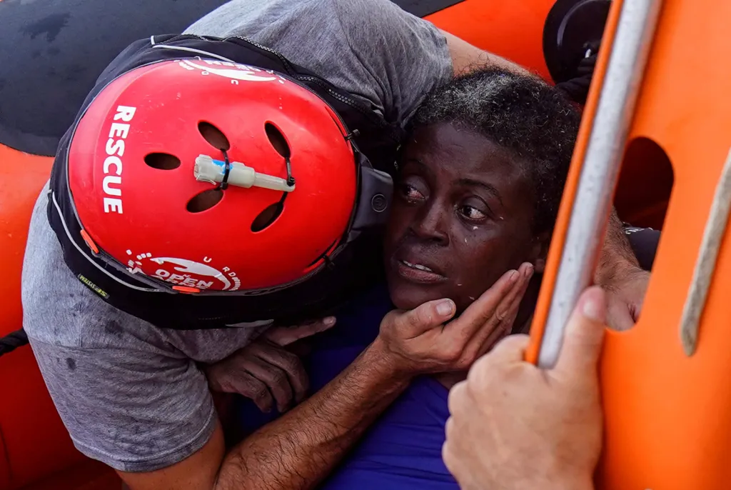Člen posádky záchranné lodi neziskovky Proactiva Open Arms objímá afrického migranta po záchranné akci ve Středozemním moři