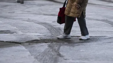 Starší žena jde po zledovatělém chodníku