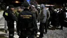 Finští pohraničníci mluví se skupinou rusky mluvících lidí na finsko-ruské hranici