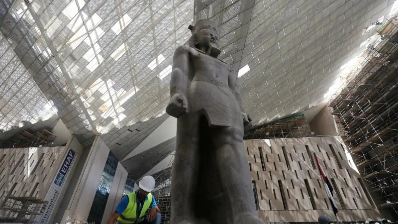 Přípravy na otevření muzea: dělník pracuje u nadživotní sochy Ramesse II.