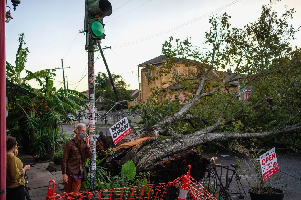 Místní před kavárnou v americkém New Orleans. Kousek od nich leží padlý strom, který porazil hurikán Zeta