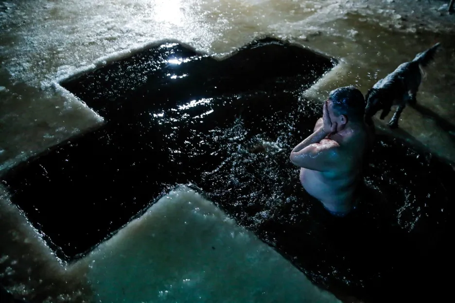 Muž se noří do ledové vody během pravoslavných oslav Zjevení Páně v osadě Šimsk v Novgorodské oblasti v Rusku