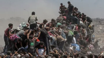 Finalista World Press Photo 2026 – Nouzová pomoc v Gaze (Aid Emergency in Gaza) – Palestinci lezou na nákladní vůz s humanitární pomocí, který vjíždí do Pásma Gazy