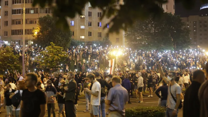 Lidé demonstrující v centru Minsku drží nad hlavami svítící displeje svých telefonů