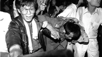 Zajatému řidiči tanku pomáhají studenti do bezpečí, zatímco ho dav bije, 4. června 1989