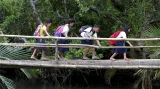 Děti z vesnice Tagumpay in Pola ve středních Filipínách překonávají v časných ranních hodinách visutý most v džungli při své každodenní šestikilometrové cestě do školy.