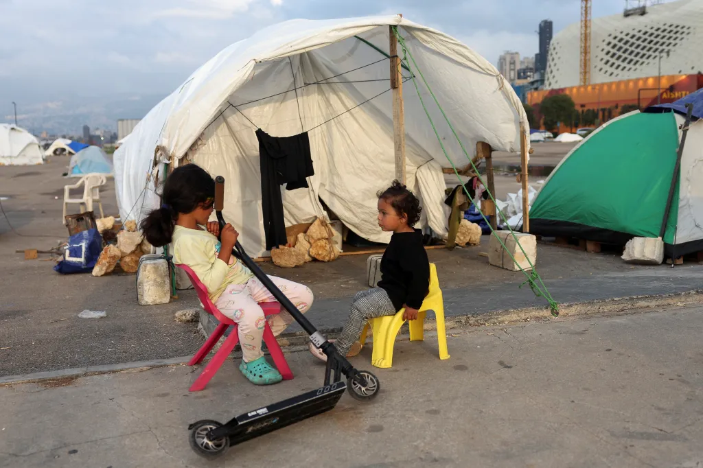 Uprchlické děti sedí před stanem v improvizovaném uprchlickém táboře