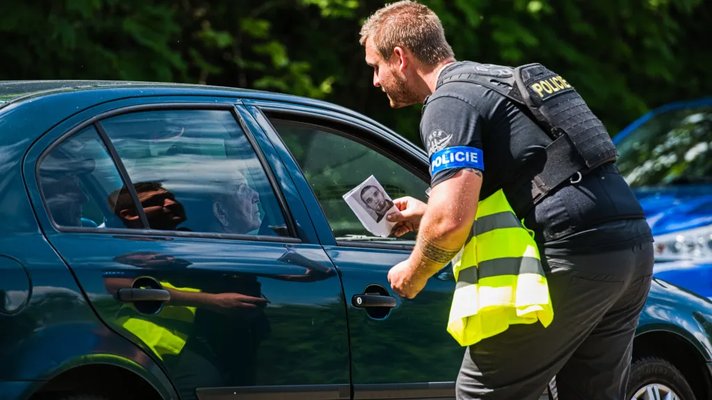 Policista s fotografií hledaného muže (5.6. 2024)