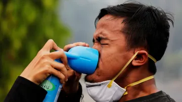 Jeden z demonstrujících v Indonésii dostává dýchnout kyslíku, protože oblast je stále zahalená dýmem z vypalovaných lesů