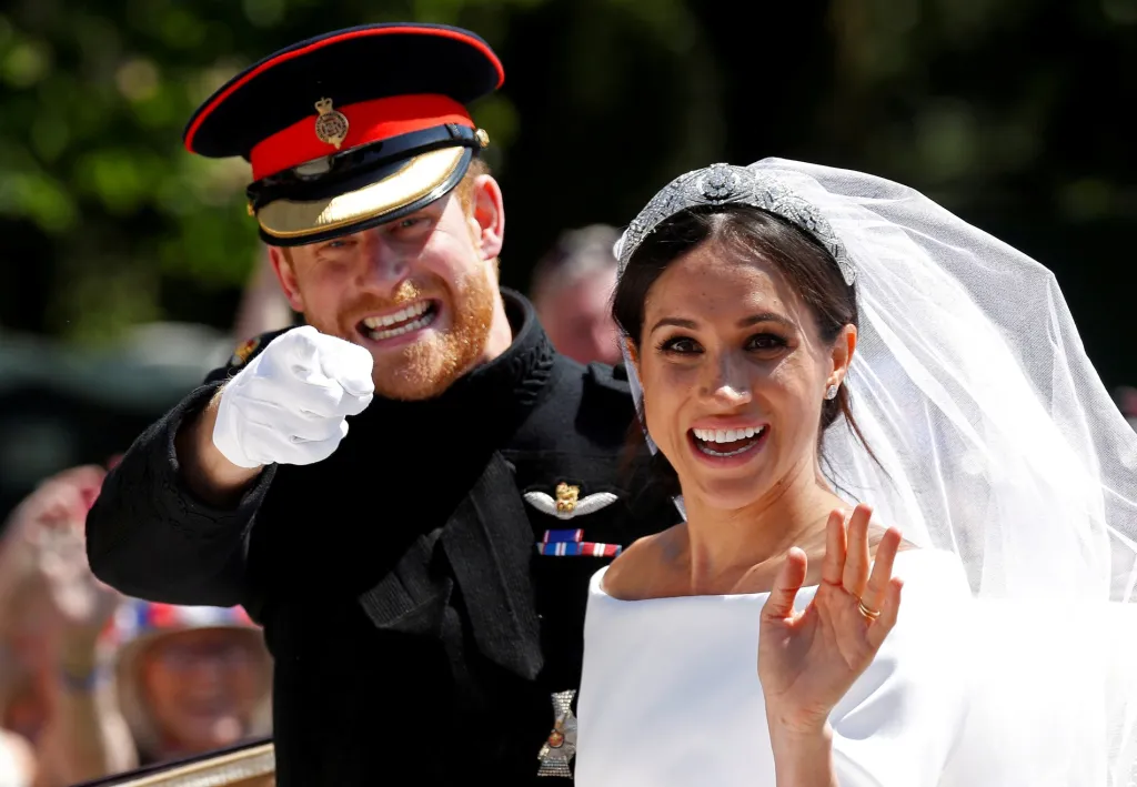 Britský princ Harry s manželkou Meghan zdraví davy během jízdy na koňském povozu po svatebním obřadu v kapli svatého Jiří na zámku Windsor, Velká Británie, 19. května 2018