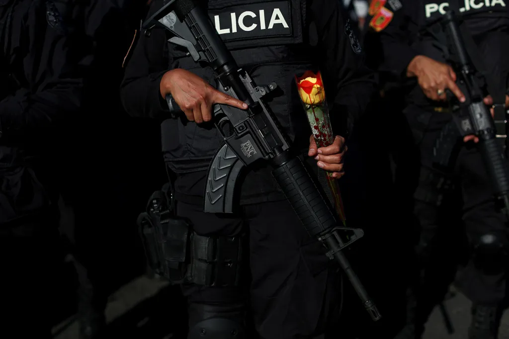 Policistka speciálních taktických ozbrojených složek známých pod názvem Jaguáři v rámci policejních sborů v El Salvadoru s puškou v jedné ruce a květinou v druhé během jejich prezentace v rámci Dne svatého Valentýna