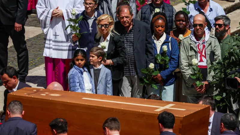 Lidé drží bílé růže u rakve papeže Františka