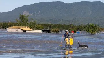 Záchranáři procházejí se psem zaplavenou oblastí