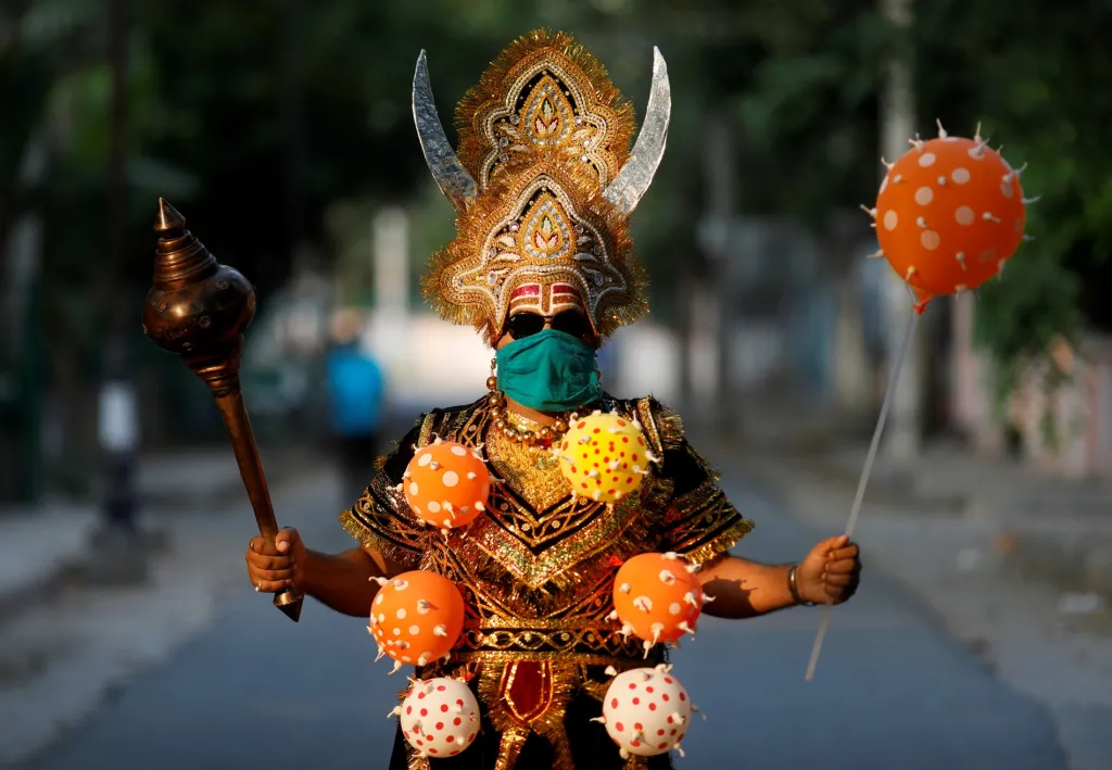 Jeden z obyvatel indického Dillí se oblékl jako hinduistický bůh smrti, který má na sobě náhrdelník s motivem koronaviru