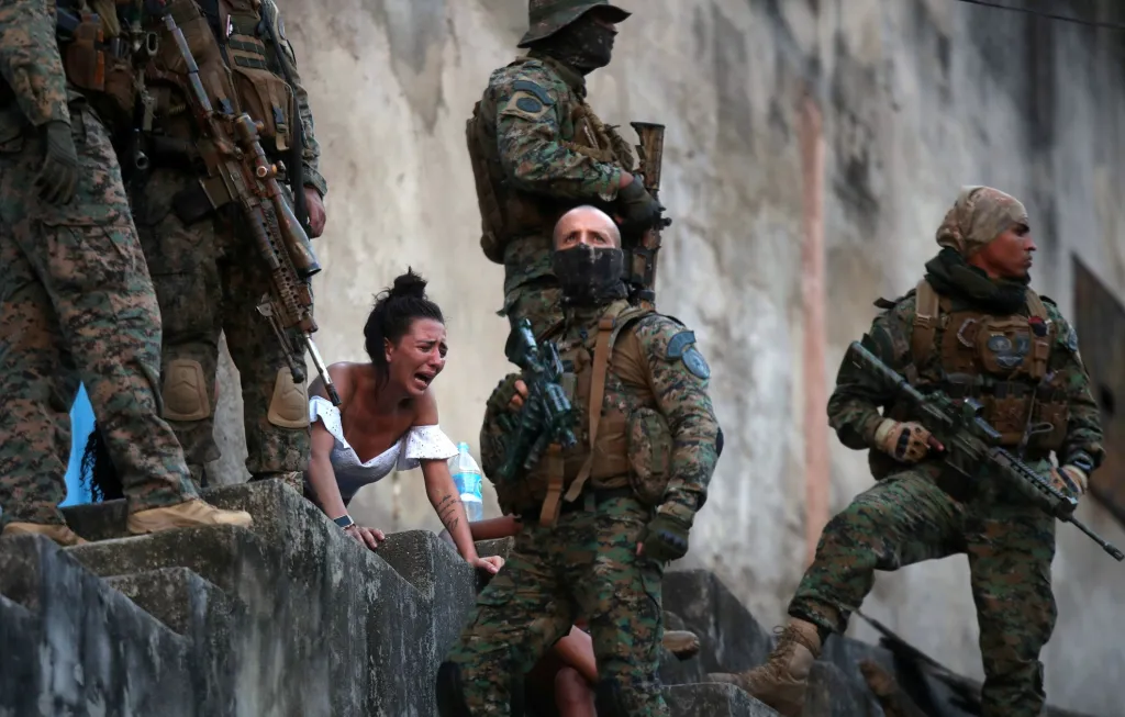 Po policejním zásahu ve slumu v brazilském Riu de Janeiro pláče žena u těla člena rodiny, který se stal obětí války místních drogových gangů