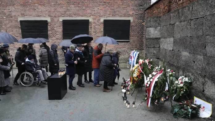 Přeživší holocaustu a jejich příbuzní pokládají svíčky u takzvané zdi smrti v Osvětimi