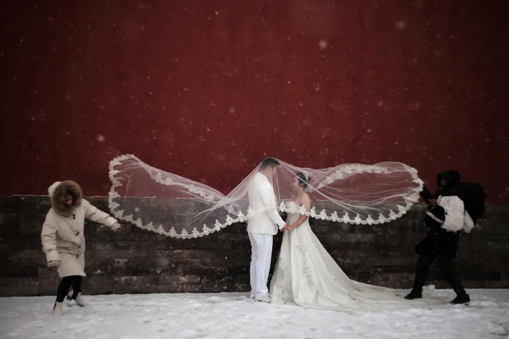 Pár novomanželů pózuje pro svatební fotografie během hustého sněžení v Pekingu