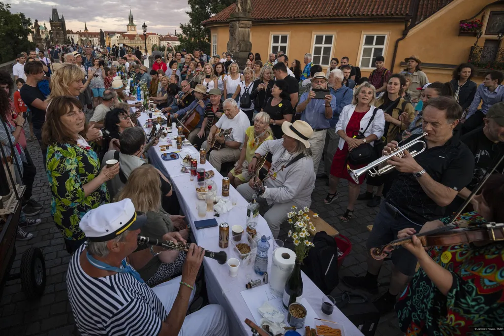 Snímek nominovaný v kategorii aktualita, Jaroslav Novák (TASR). Lidé se baví během hostiny za přibližně půlkilometrovým stolem na pražském Karlově mostě 30. června 2020. Velkolepá hostina měla být podle organizátorů symbolickým rouzloučením s koronavirovou krizí