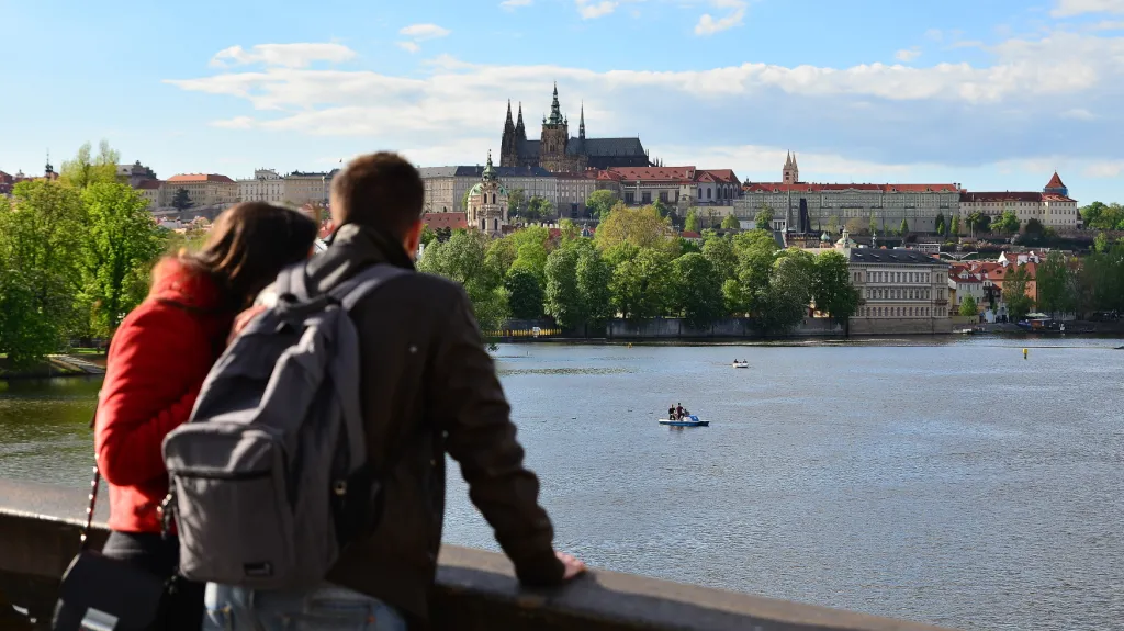 Turisté hledící na panorama s Pražským hradem a řekou Vltavou